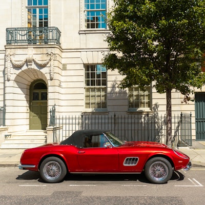 Photo of a Ferrari parked at the front of a Palladian building.