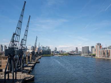 View of Royal Victoria Dock, a huge empty expanse of water lined with cranes.