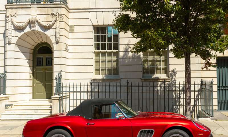 Photo of a Ferrari parked at the front of a Palladian building.