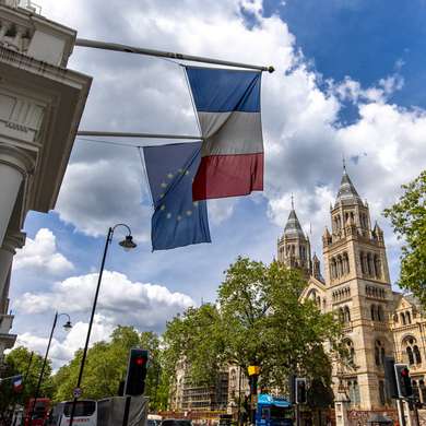 Photo of The Natural History Museum in South Kensington, with a French flag in the foreground