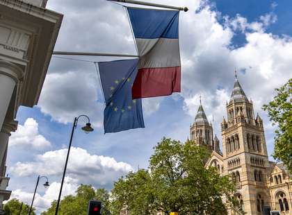 Photo of The Natural History Museum in South Kensington, with a French flag in the foreground