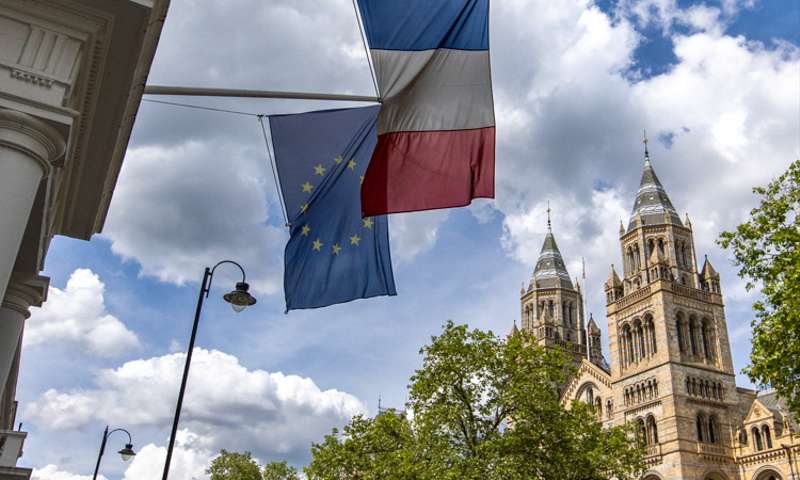 Photo of The Natural History Museum in South Kensington, with a French flag in the foreground