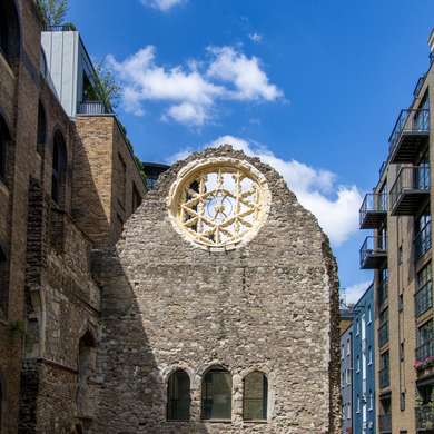 Photo of a flint wall with a rose window, part of some ruins