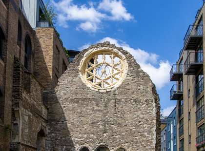 Photo of a flint wall with a rose window, part of some ruins