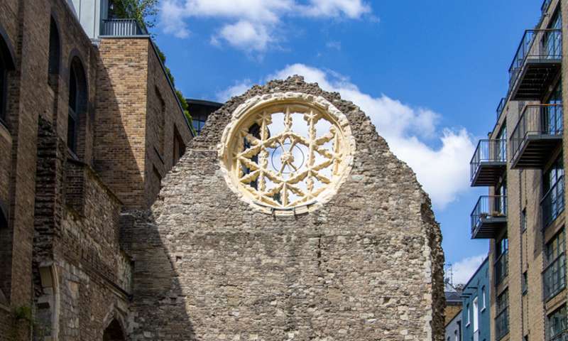 Photo of a flint wall with a rose window, part of some ruins