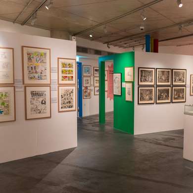 Photo of the interior of the Cartoon Museum, situated in a basement with cartoons on the walls.