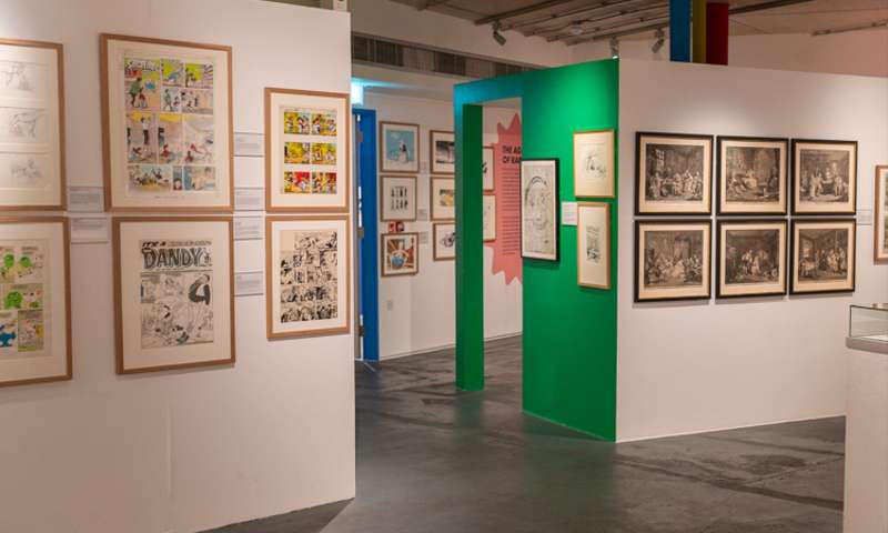 Photo of the interior of the Cartoon Museum, situated in a basement with cartoons on the walls.