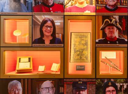 Photographs of chelsea pensioners on a wall, with some items in display cases.