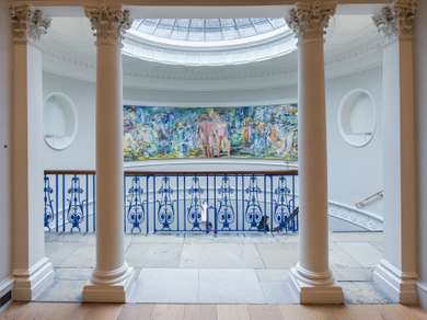 A large contemporary painting can be seen through a doorway. The ceiling is a glass dome that provides lots of natural light.