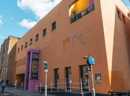 Photo of the exterior of the museum, a modern, orange building