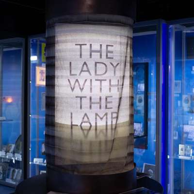 Photo of a large replica lamp with "The Lady of the Lamp" projected onto it.