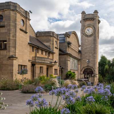 Photo of the clock tower with blue flowers in the foreground.