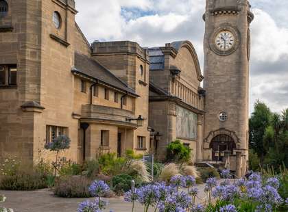 Photo of the clock tower with blue flowers in the foreground.