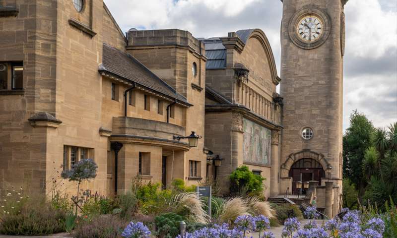 Photo of the clock tower with blue flowers in the foreground.