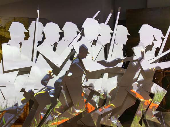 A video is projected onto an angular backdrop depicting advancing soldiers.