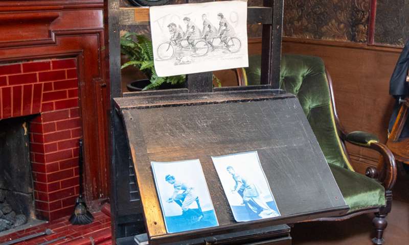 A desk with a sketch of some people on a tandem alongside photographs of the same.