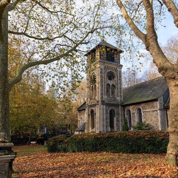 St Pancras Old Church, framed by trees with autumn leaves covering the ground.