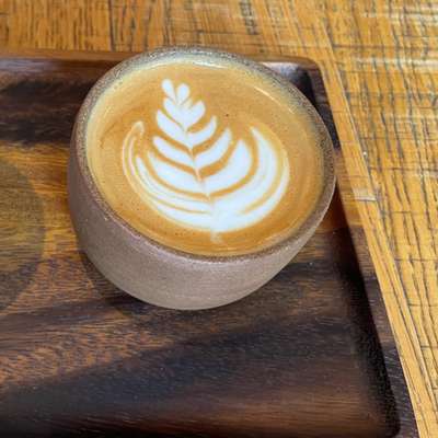 Photo of a flat white in a kind of earthenware cup thing with no handle.