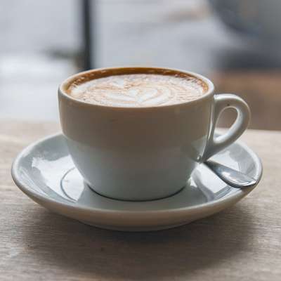 A flat white on a wooden table outside Store Street Espresso on a grey day