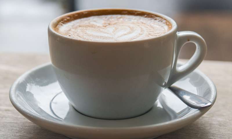 A flat white on a wooden table outside Store Street Espresso on a grey day